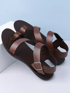Detail view of stylish brown men's sandals with an adjustable buckle ankle strap.