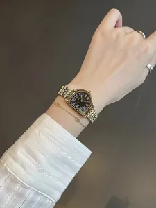 Primer plano de un elegante reloj vintage dorado para mujer con números romanos en la muñeca.