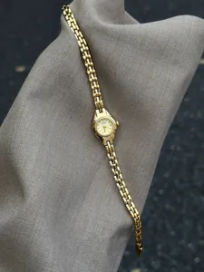 Vue détaillée d'une élégante petite montre GEDI vintage en or pour femme sur tissu gris