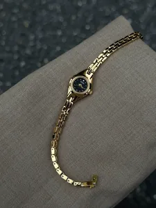 Détail d'une montre à quartz dorée vintage pour femme avec un cadran noir sophistiqué