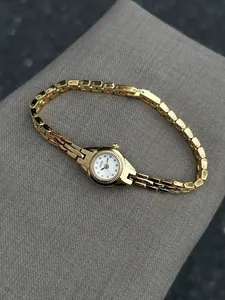 Vue détaillée d'une montre à quartz vintage dorée pour femme avec un bracelet fin.