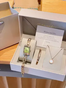 Détail d'un coffret cadeau de luxe vintage avec montre dorée, bracelet et collier.