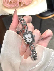 Close-up of vintage silver quartz watch with elegant rectangular dial and chain strap.