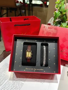 Nahaufnahme des eleganten Sets aus goldener Uhr und Diamantarmband in einer roten Box.