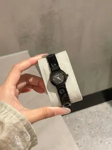 Primo piano di un orologio al quarzo nero da donna con cinturino in acciaio traforato.
