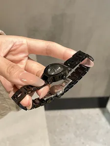 Primo piano di un orologio al quarzo da donna in acciaio nero traforato tenuto in mano.