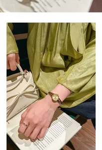 Elegante reloj vintage dorado de mujer con anillo a juego y bolso crema con lazo.