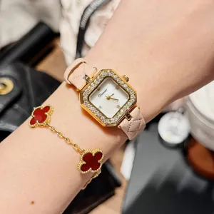 Close-up view of a pink quilted leather watch and a red clover bracelet on a wrist