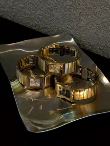 Primer plano de tres relojes de cuarzo retro rectangulares de oro y acero para mujer.