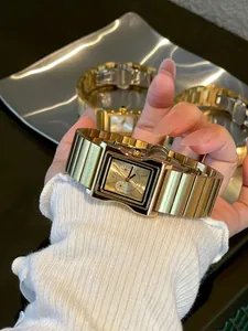 Primer plano del reloj de cuarzo cuadrado dorado GUOU en mano, detalles de la correa.