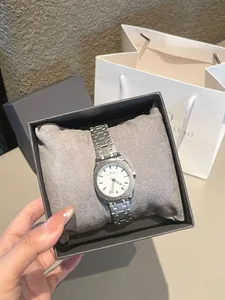 Primer plano de un reloj cuadrado plateado minimalista para mujer con correa de acero