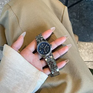 Primer plano de un moderno reloj de acero plateado con esfera azul sostenido en la mano