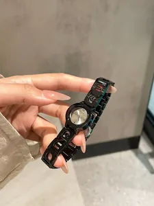 Dettaglio di un orologio al quarzo da donna con cinturino in acciaio a maglie nere traforate.