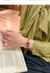 Reloj vintage dorado para mujer con esfera roja y una elegante blusa de seda verde