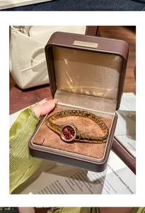 Reloj vintage para mujer con esfera roja y brazalete dorado en un estuche de joyería marrón