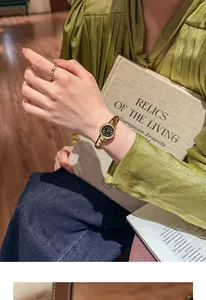 Primer plano de un reloj de lujo vintage dorado en la muñeca con camisa de seda verde.