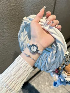 Montre bracelet carrée élégante pour femme ton argent portée avec un sac à main blanc