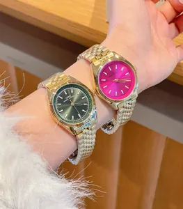 Primo piano di orologi di lusso in acciaio dorato con vivaci quadranti rosa e verdi