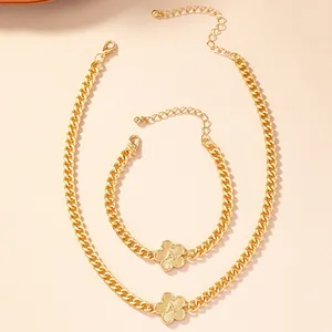 Close-up of gold flower pendant with letter A on a chunky curb chain jewelry set.