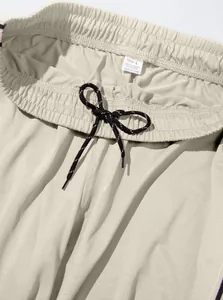 Close-up of men's beige sweatpants waistband with drawstring and size label