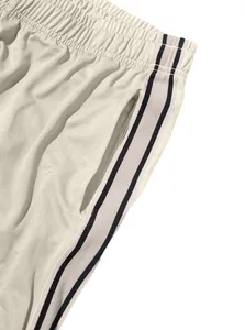 Close-up detail of men's wide-leg track pants with striped side tape and pocket