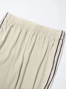 Macro view of men's twill sweatpants showing elastic waistband and side stripe detail.