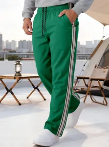 Detail view of green men's straight leg sweatpants with white and black side stripes
