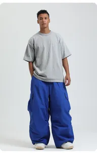 Full body view of loose blue waterproof snowboarding cargo pants on male model