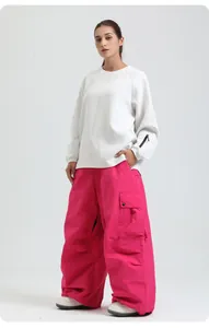 Full body view of women's loose waterproof pink snowboarding pants and white top
