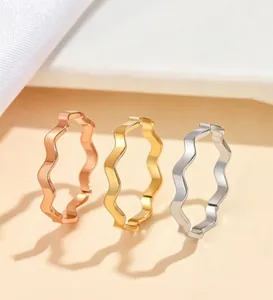 Three minimalist stainless steel wavy band rings in gold, silver, and rose gold finishes.