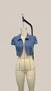 Vista dettagliata di un coprispalle in denim azzurro con maniche corte a sbuffo su manichino.