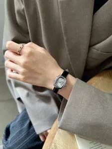 Nahaufnahme einer Vintage-Quarzuhr für Damen mit schwarzem Armband und römischen Ziffern