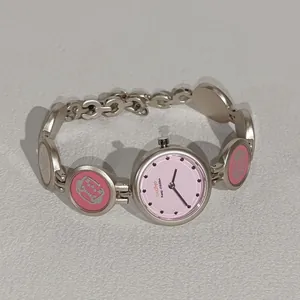 Detailaufnahme einer modischen Armbanduhr mit rosa Zifferblatt und Charms für Mädchen