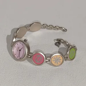Nahaufnahme einer Armbanduhr für Schüler mit rosa Zifferblatt und bunten Anhängern.