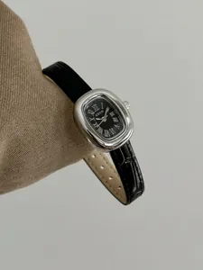 Elegante Nahaufnahme einer klassischen ovalen Quarzuhr für Damen mit schwarzem Zifferblatt.