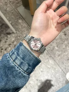 Detailansicht einer luxuriösen Dinimi-Damenuhr mit Strass und rosa Zifferblatt am Handgelenk