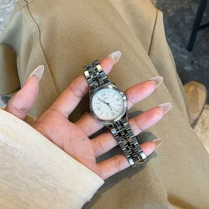 Primer plano de un reloj de acero plateado con bisel estriado sostenido en mano