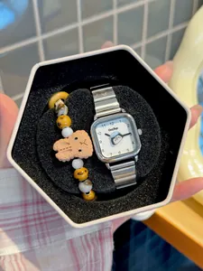 Detalle de un reloj de cuarzo cuadrado con pingüino y pulsera de cuentas en una caja de regalo