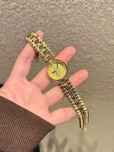 Detail view of a vintage-style gold bracelet watch with a textured round dial.