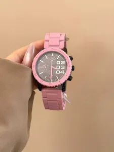 Primer plano de un reloj de cuarzo rosa con esfera negra grande y correa de silicona
