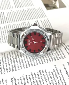 Dettaglio di un orologio minimalista in acciaio argento con un vivace quadrante rosso.