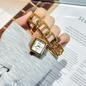 Close-up detail of a vintage gold steel band watch featuring an elegant rectangular face