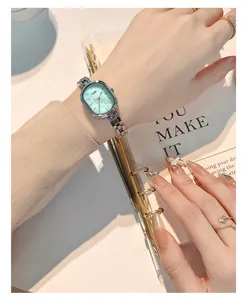 Elegante reloj ovalado plateado con esfera verde menta en la muñeca de una mujer