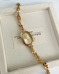 Detail view of an elegant vintage gold-toned women's watch with chain bracelet.
