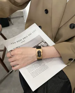 Vintage rectangular gold watch with black leather strap worn with a tan blazer