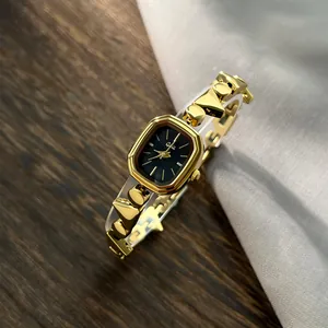 Close-up detail of an elegant gold irregular bracelet watch with a sleek black dial