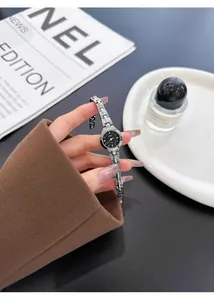 Primer plano de un elegante reloj de pulsera plateado con esfera negra sostenido a mano