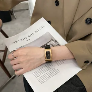 Elegant vintage gold rectangular watch with black leather strap on female wrist.