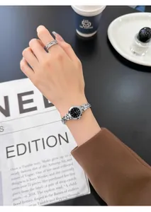 Vista macro de un reloj de pulsera plateado con esfera negra y anillo de diamante