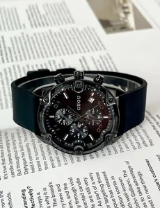 Close-up detail of GUOU black chronograph watch with silicone strap on a magazine